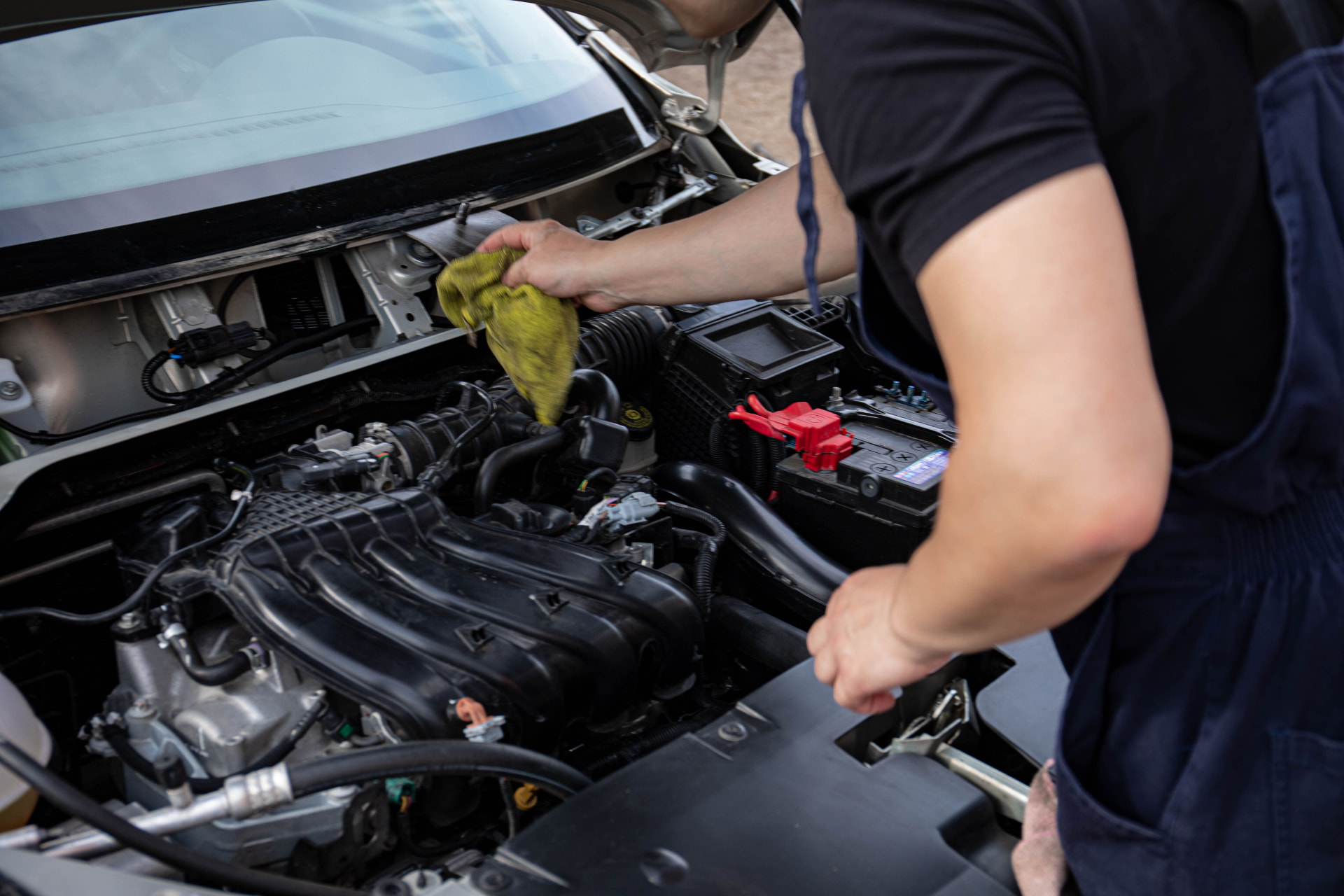 Engine bay cleaning service - detailer wiping down a car engine compartment