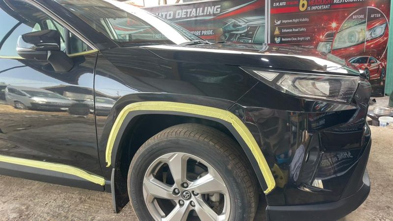 Black Toyota RAV4 masked with tape before machine polishing