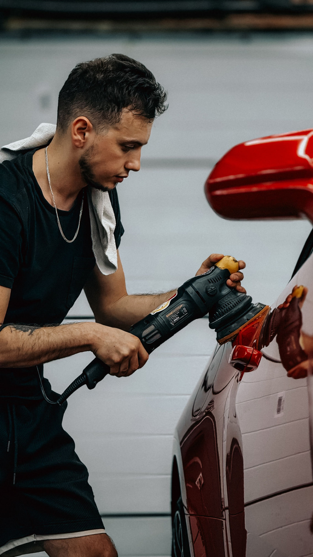 Mobile detailing service - detailer machine polishing the side of a red car