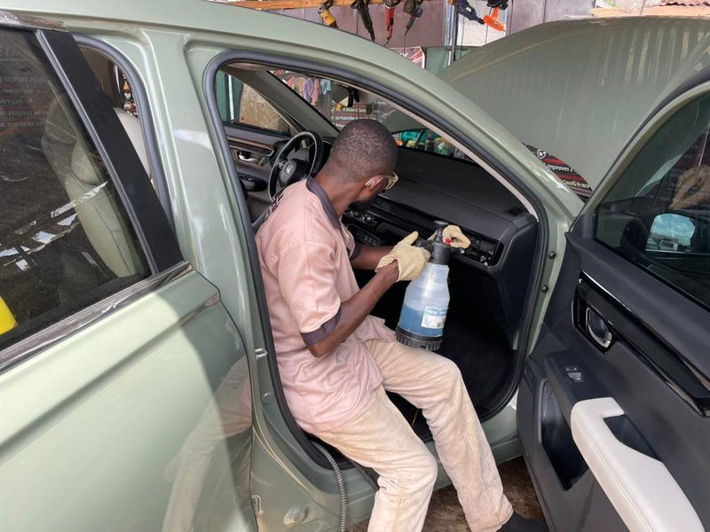DOLAMOTORS AUTO DETAILING technician treating a dashboard and vents by hand